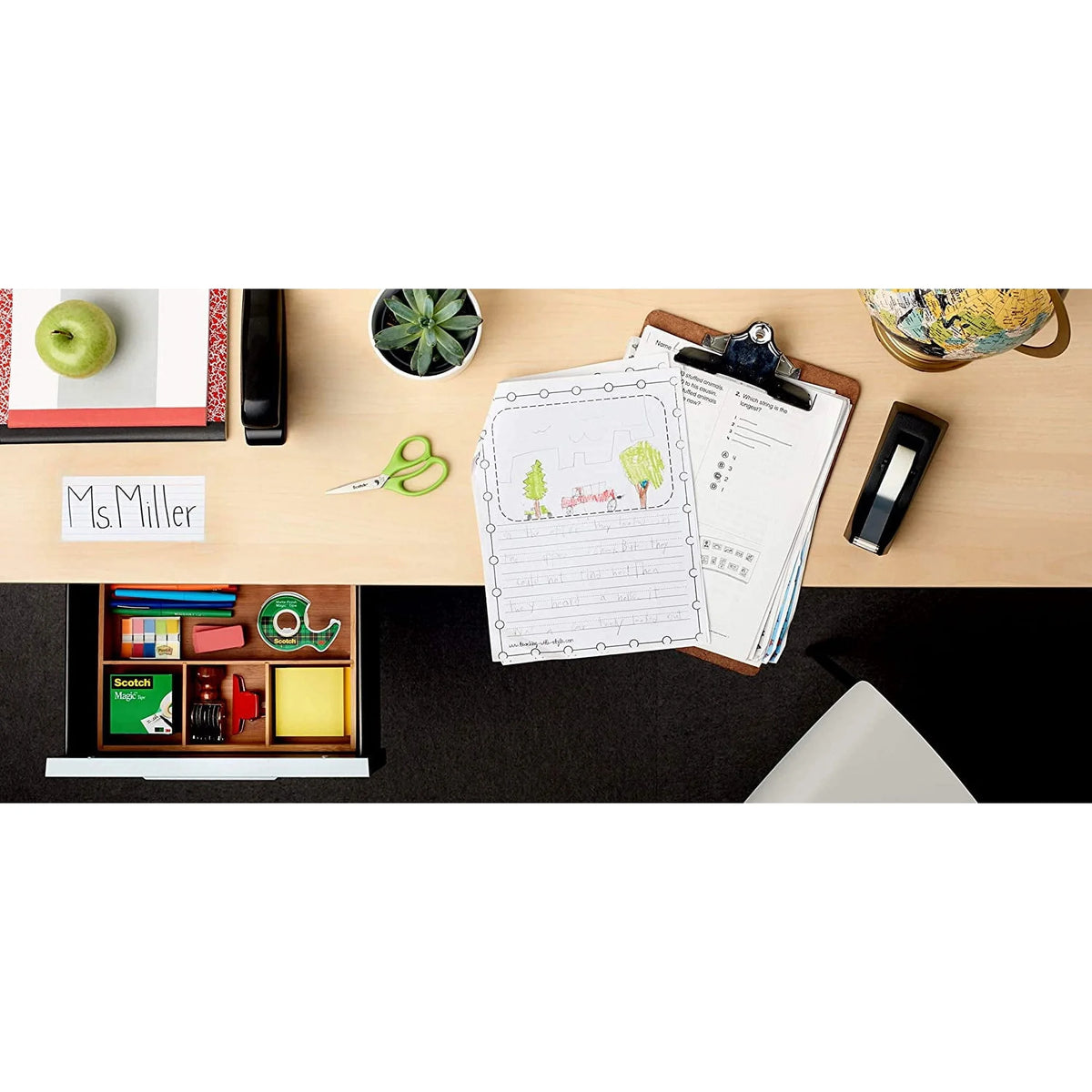 Desk with stationery items including a clipboard with papers, scissors, and a box of crayons.