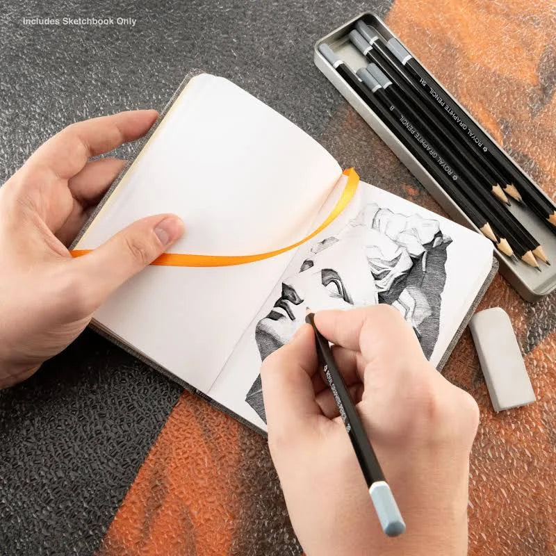 Person drawing in a sketchbook with pencils and an eraser on a textured surface